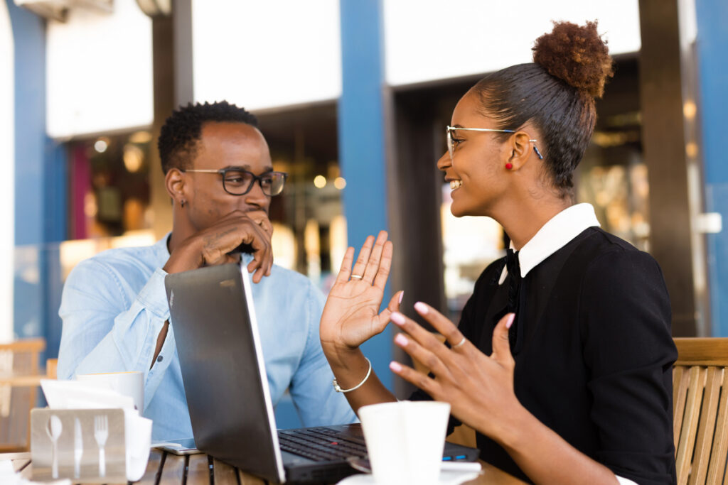 Two young professionals engaged in a conversation in an outdoor cafe setting